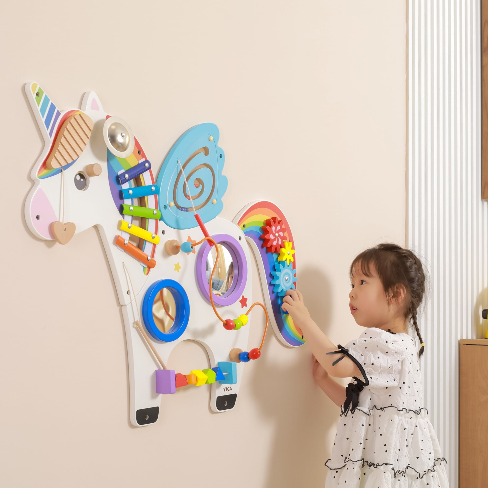 Dziewczynka bawi się drewnianą tablicą manipulacyjną Jednorożec VIGA – sensoryczna tablica Montessori na ścianę