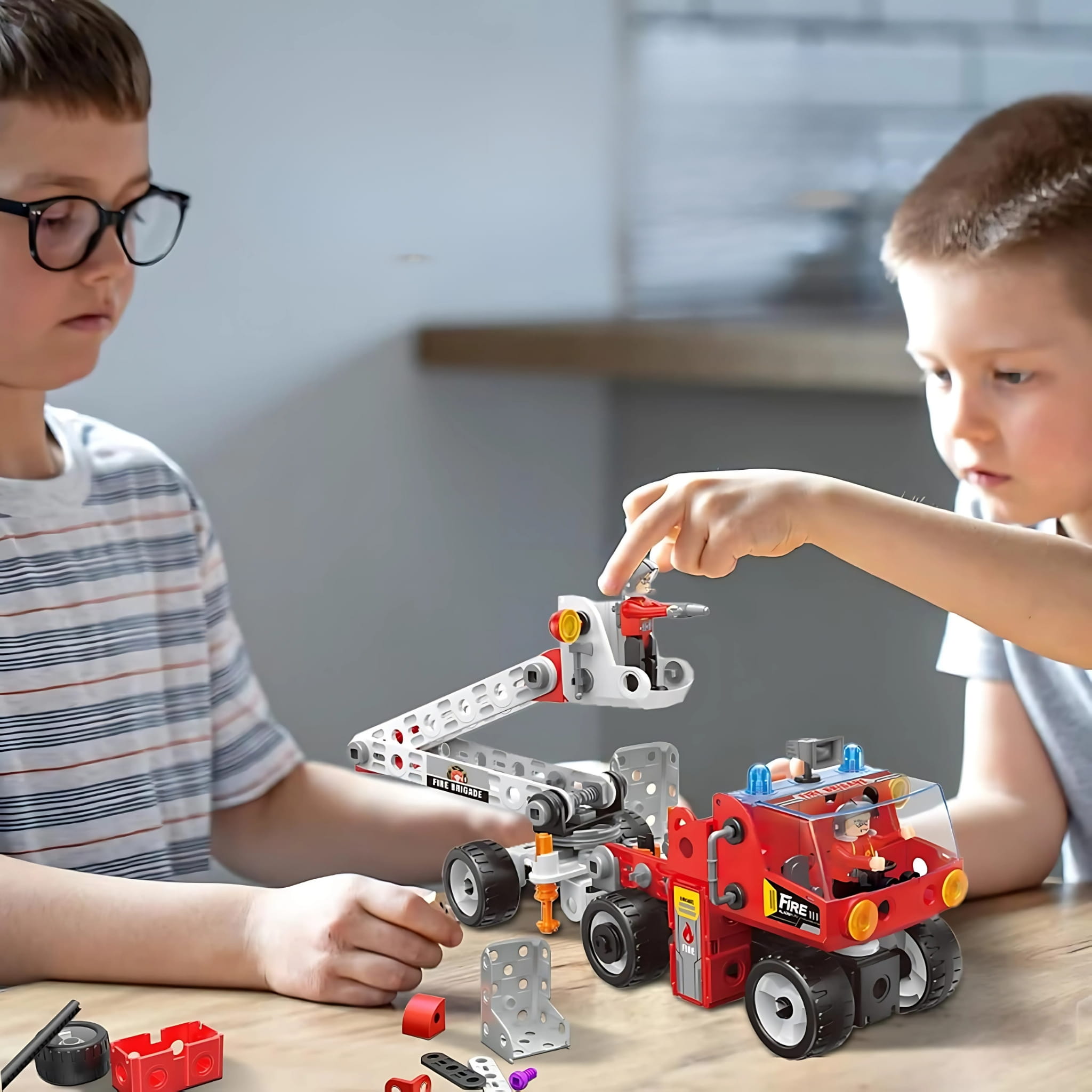 Dwóch chłopców budujących wóz strażacki z klocków konstrukcyjnych STEM rozwijających logiczne myślenie, kreatywność i zdolności techniczne.